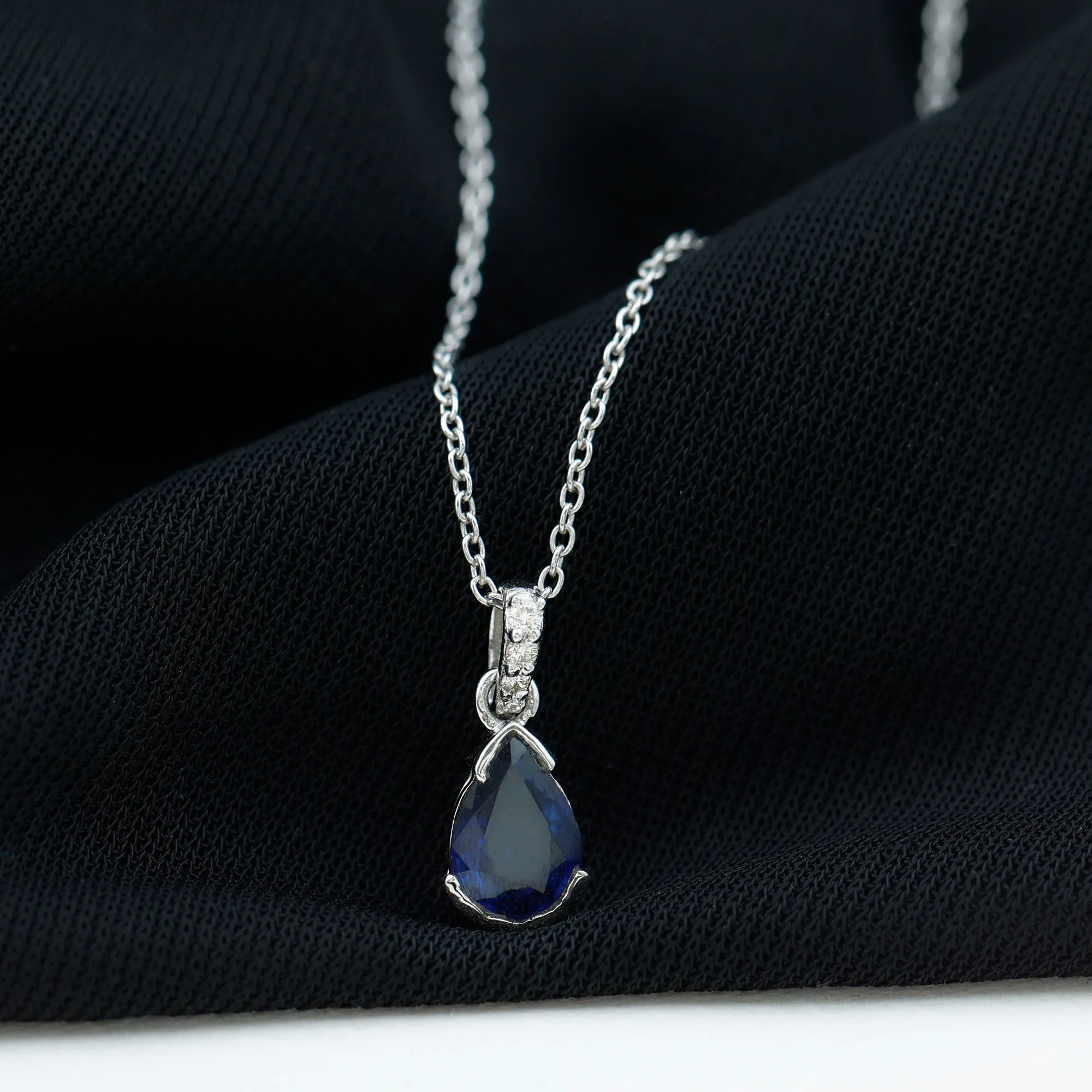 1 CT Pear Cut Blue Sapphire Solitaire Pendant in Half Bezel Setting with Diamond Accent Bail